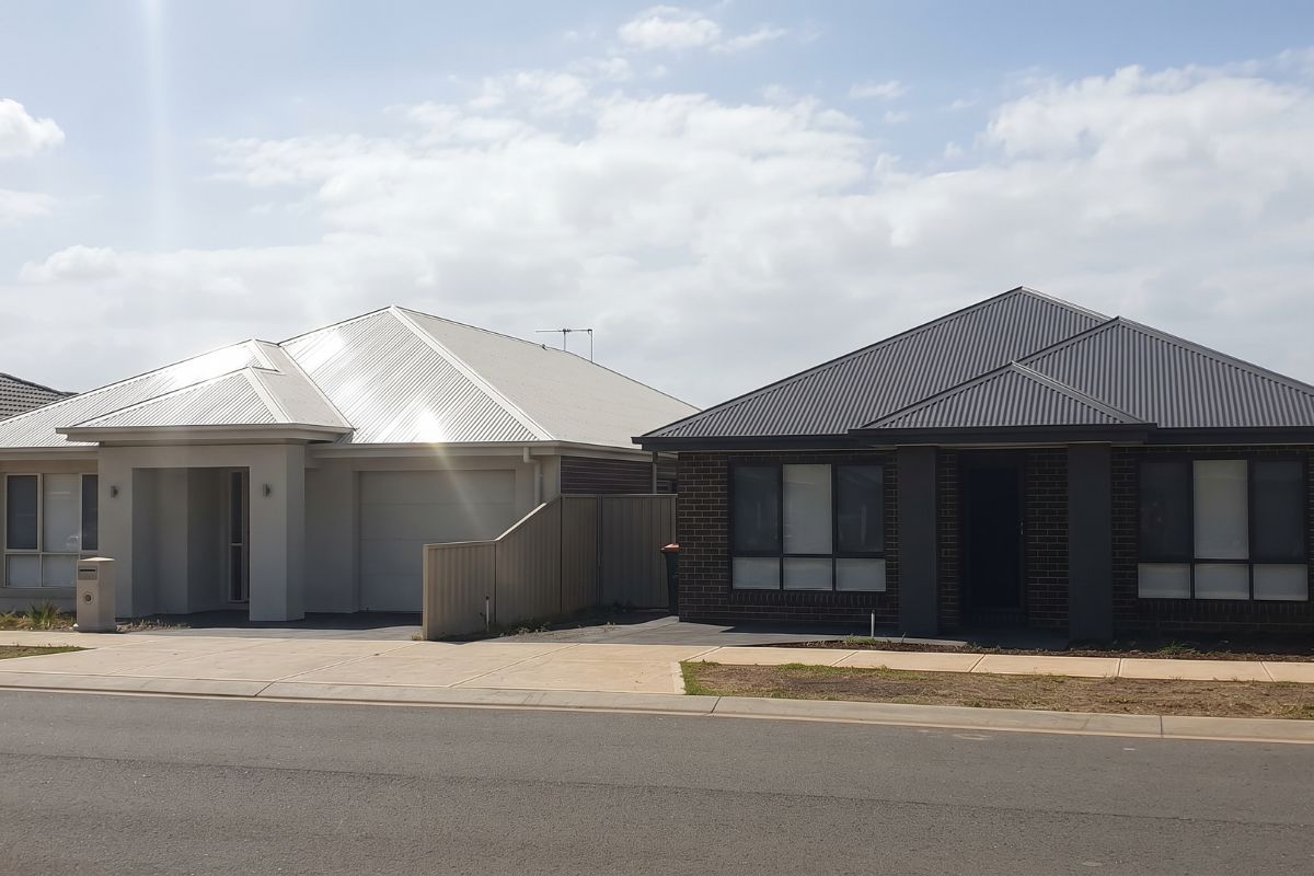 Colorbond Roofing: Benefits, Drawbacks, Costs and How to Choose 3 Two houses side by side, one with a pale steel roof and one with a dark charcoal roof